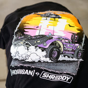Black short sleeve t-shirt featuring vibrant graphic of a desert off-road vehicle with a sunset backdrop, showcasing Hoonigan x Shreddy collaboration.