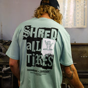 Men's mint green short sleeve t-shirt featuring bold "SHRED ALL TIRES" graphic on the back, perfect for motorsport enthusiasts.