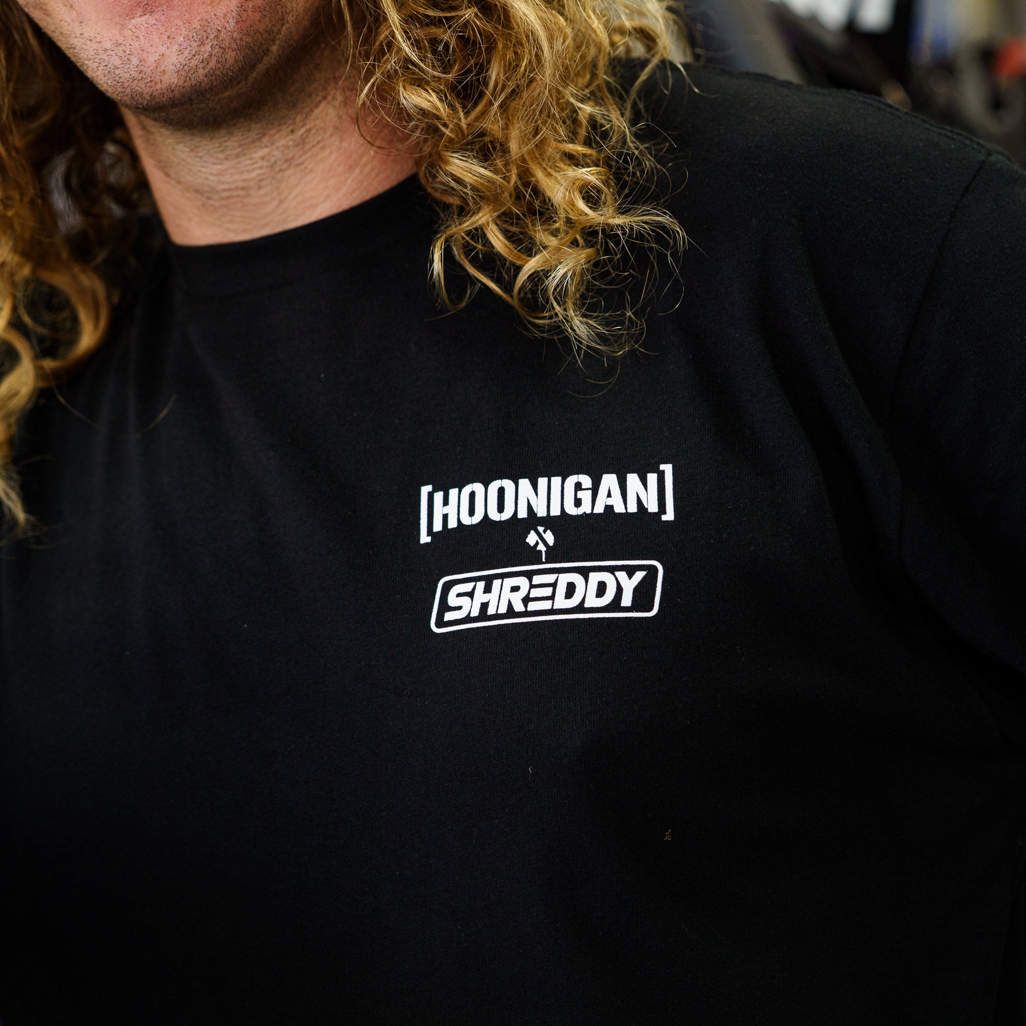 Black long sleeve t-shirt featuring Hoonigan and Shreddy logos, perfect for motorsport enthusiasts and car culture fans.
