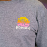 Gray short sleeve t-shirt featuring a colorful Hoonigan logo with a desert-inspired design. Perfect for motorsport enthusiasts.