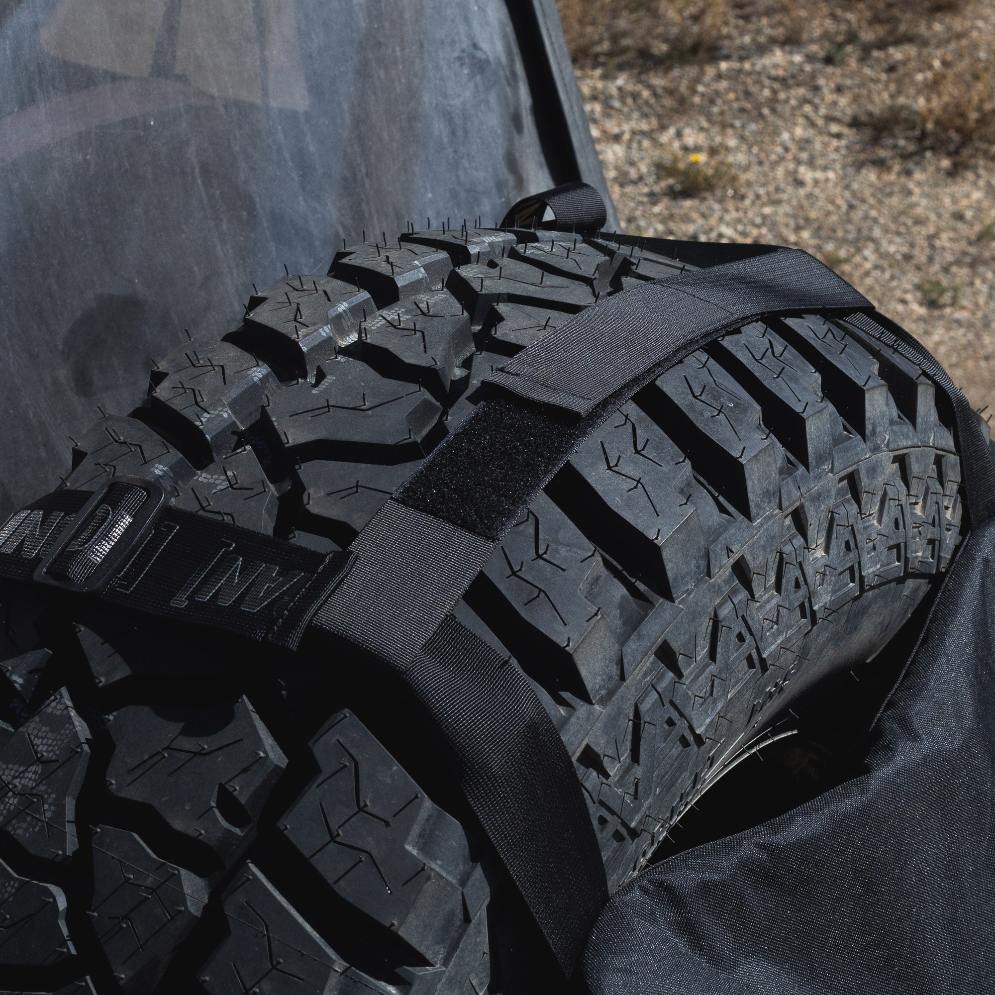 Hoonigan CENSOR BAR Spare Tire Backpack securely attached to a rugged tire, designed for automotive enthusiasts.