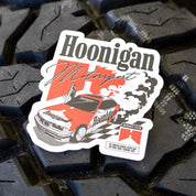 Hoonigan BURNOUT TEAM sticker featuring a classic car with smoke and checkered flag design on a tire background.