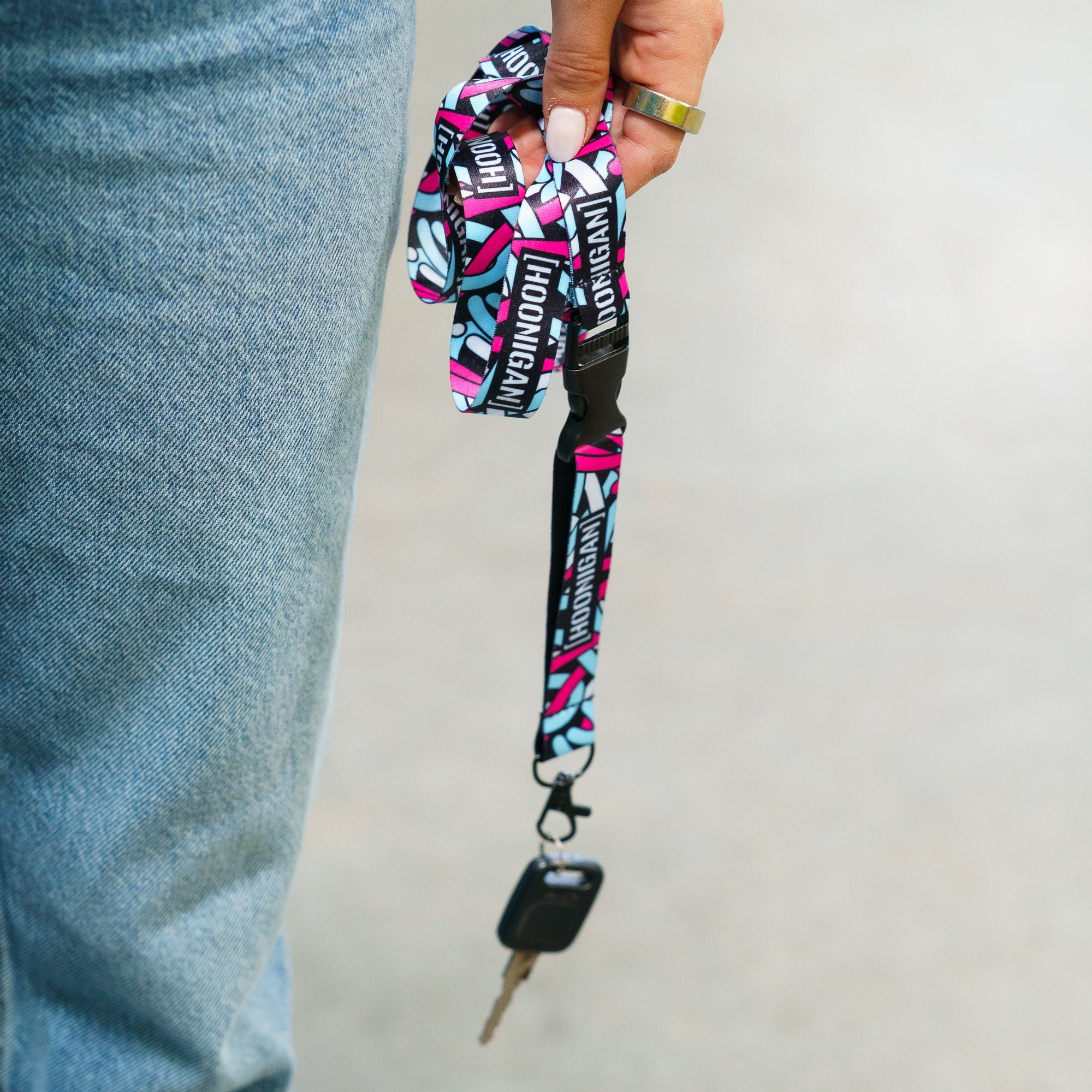 Hoonigan x Lia Block SCRIPT lanyard featuring vibrant graphics, held in a hand with car keys attached.