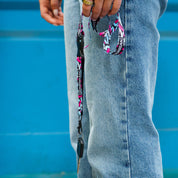 Hoonigan x Lia Block SCRIPT lanyard displayed with keys, featuring a vibrant design against denim jeans.