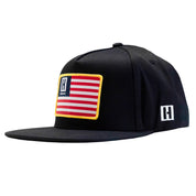 Black snapback hat featuring a bold American flag patch and Hoonigan logo, perfect for motorsport enthusiasts.
