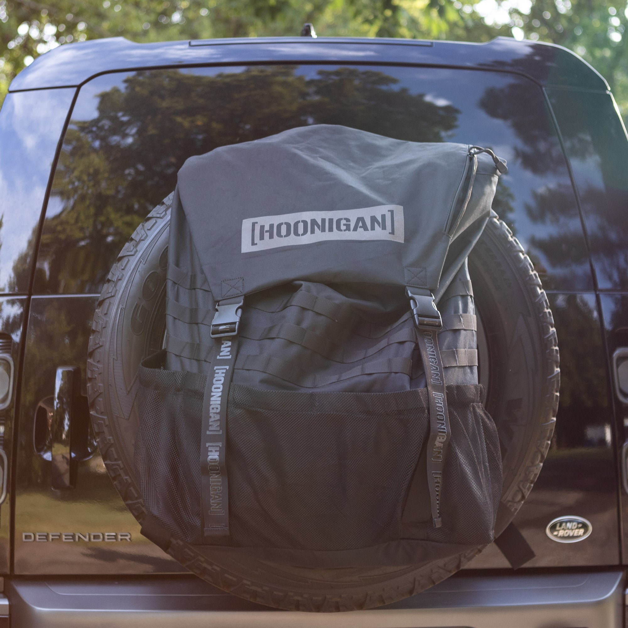 Hoonigan CENSOR BAR spare tire backpack attached to a vehicle, designed for motorsport enthusiasts and outdoor adventures.