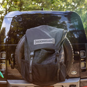 Hoonigan CENSOR BAR spare tire backpack attached to a vehicle, designed for motorsport enthusiasts and outdoor adventures.