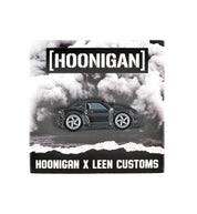Hoonigan x Leen Customs COALMARO collectible pin featuring a detailed black car design on a cloud background.