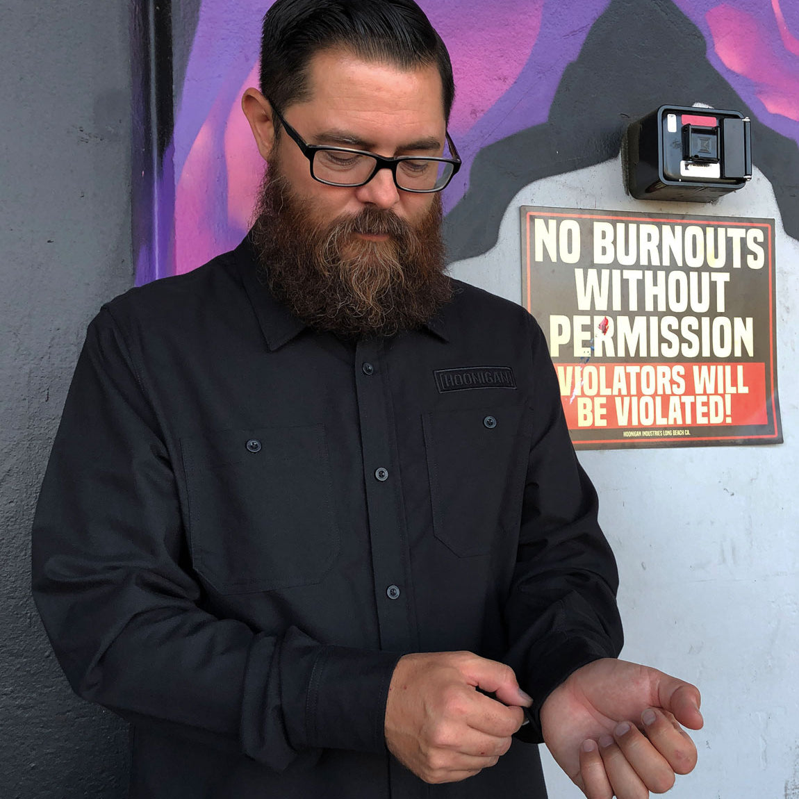 Hoonigan DONUT GARAGE black woven long sleeve button-up shirt displayed on a hanger.