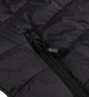 Close-up of a black GRILLE puffer vest showing a durable zipper and quilted, insulated fabric for warmth and style.